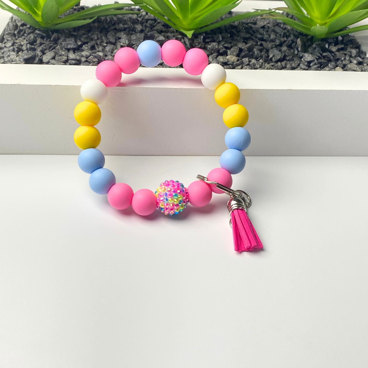 Colorful beaded bracelet with a tassel charm on a white surface.