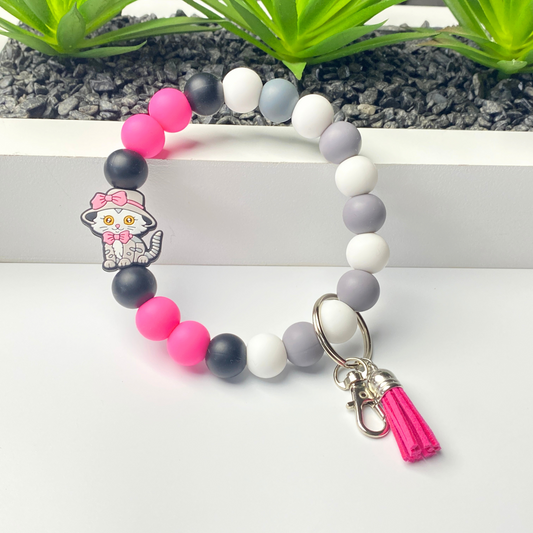 Beaded bracelet with colorful beads and a keychain charm on a white surface.
