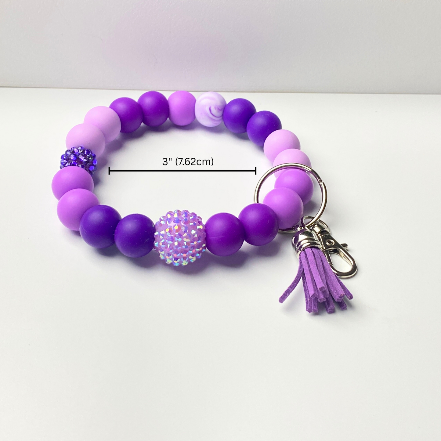 Purple beaded keychain with a tassel on a white background