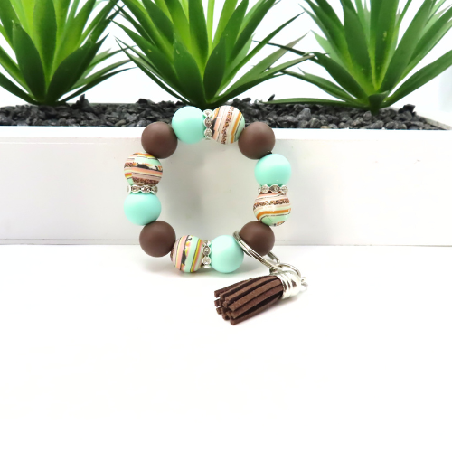 Beaded bracelet with tassel on a white background with green plants in the background