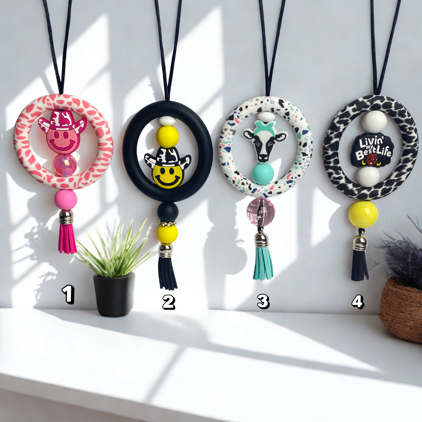 Four colorful necklaces with animal-themed beads on a white surface.