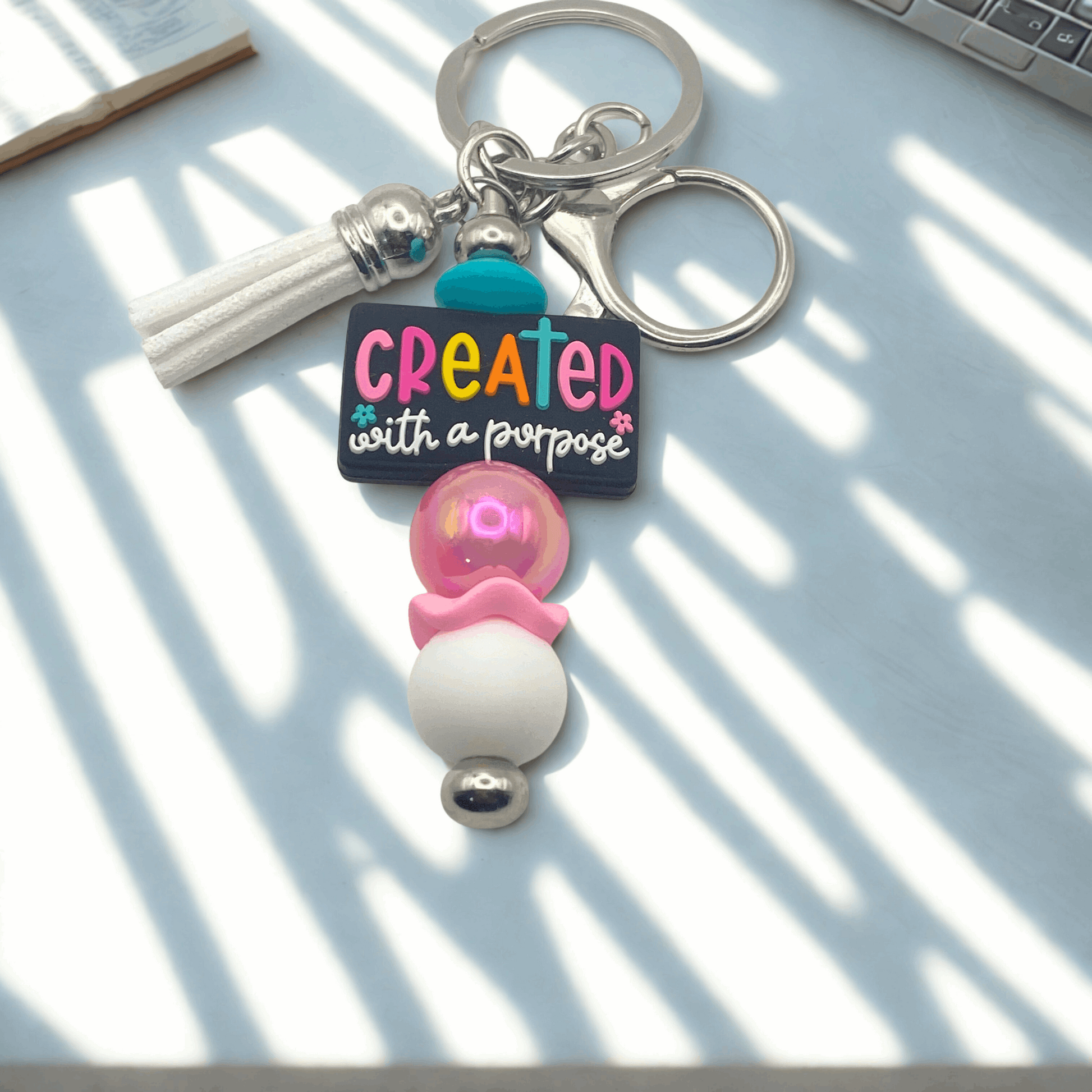 Keychain with colorful beads and motivational quote on a light surface
