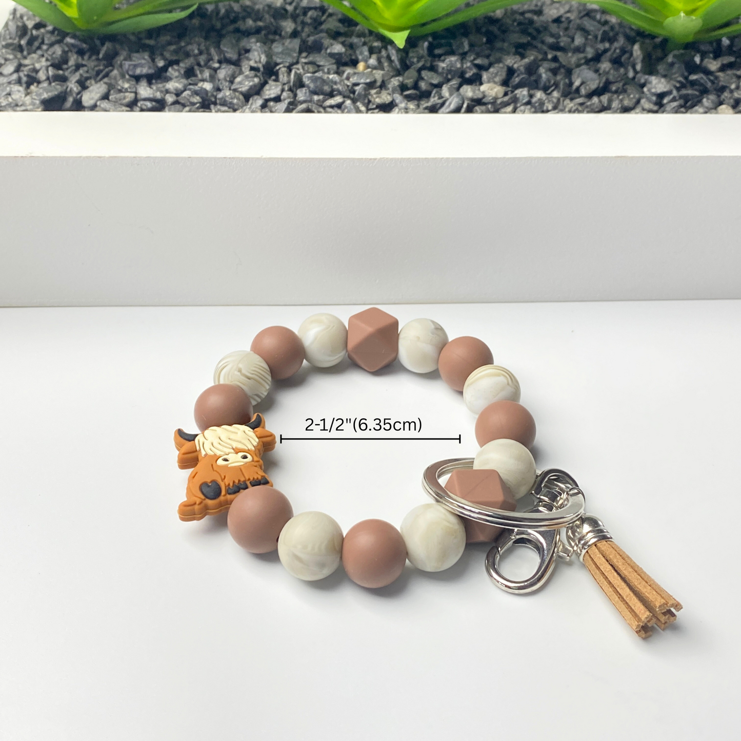 Bracelet with brown, white, and beige beads and a keychain on a white background
