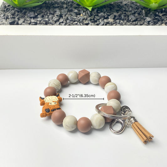 Bracelet with brown, white, and beige beads and a keychain on a white background