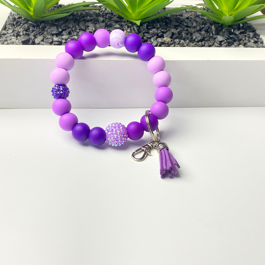 Purple beaded bracelet with a keychain on a white background