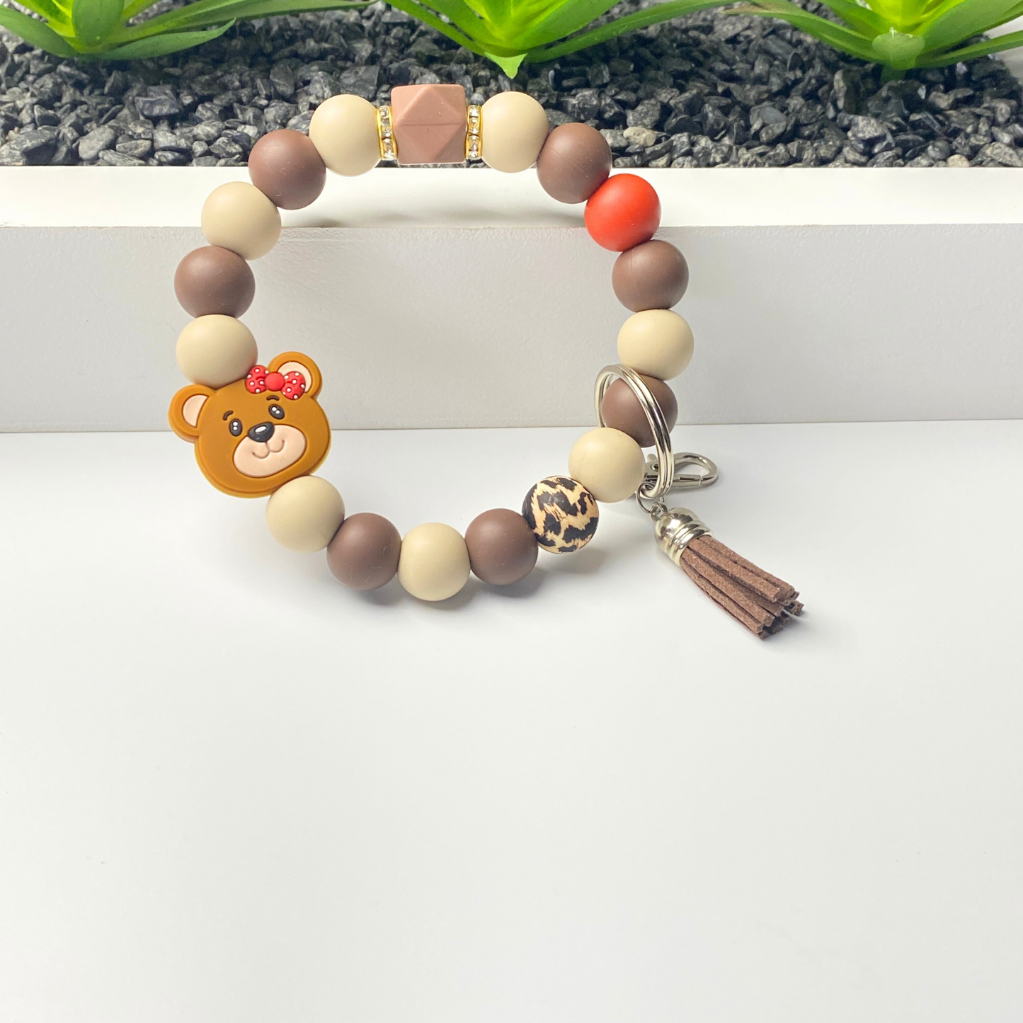 Colorful beaded bracelet with a bear charm and tassel on a white background