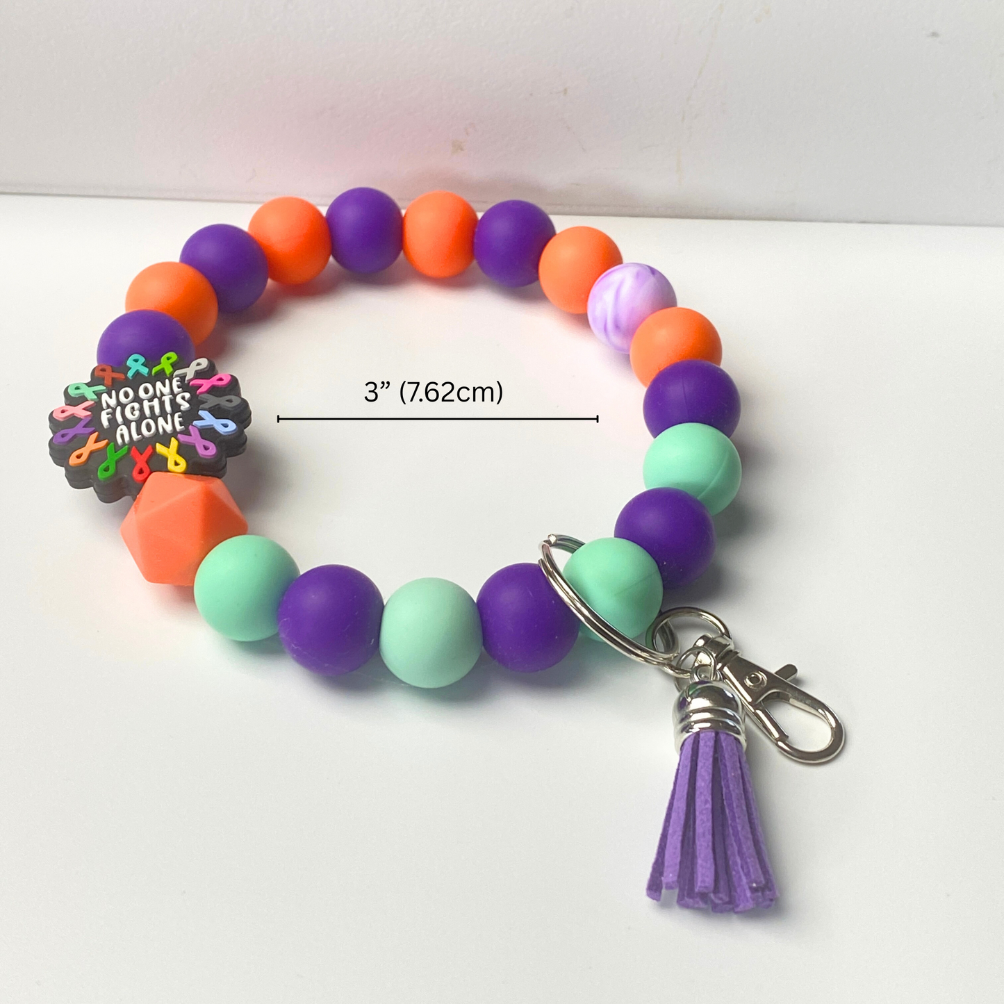 Colorful beaded bracelet with a tassel charm on a white background