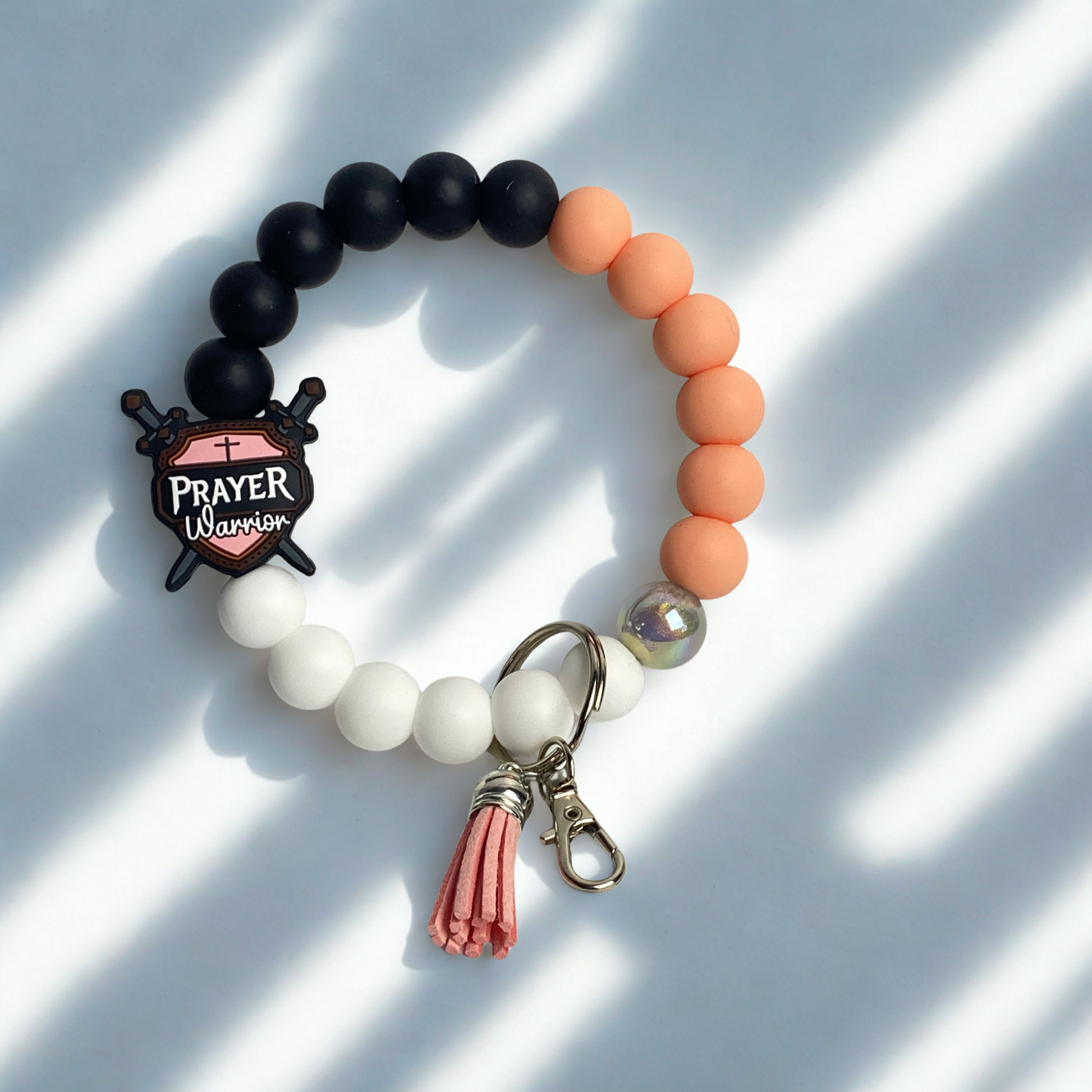Beaded bracelet with black, orange, and white beads, and a keychain charm on a light background.