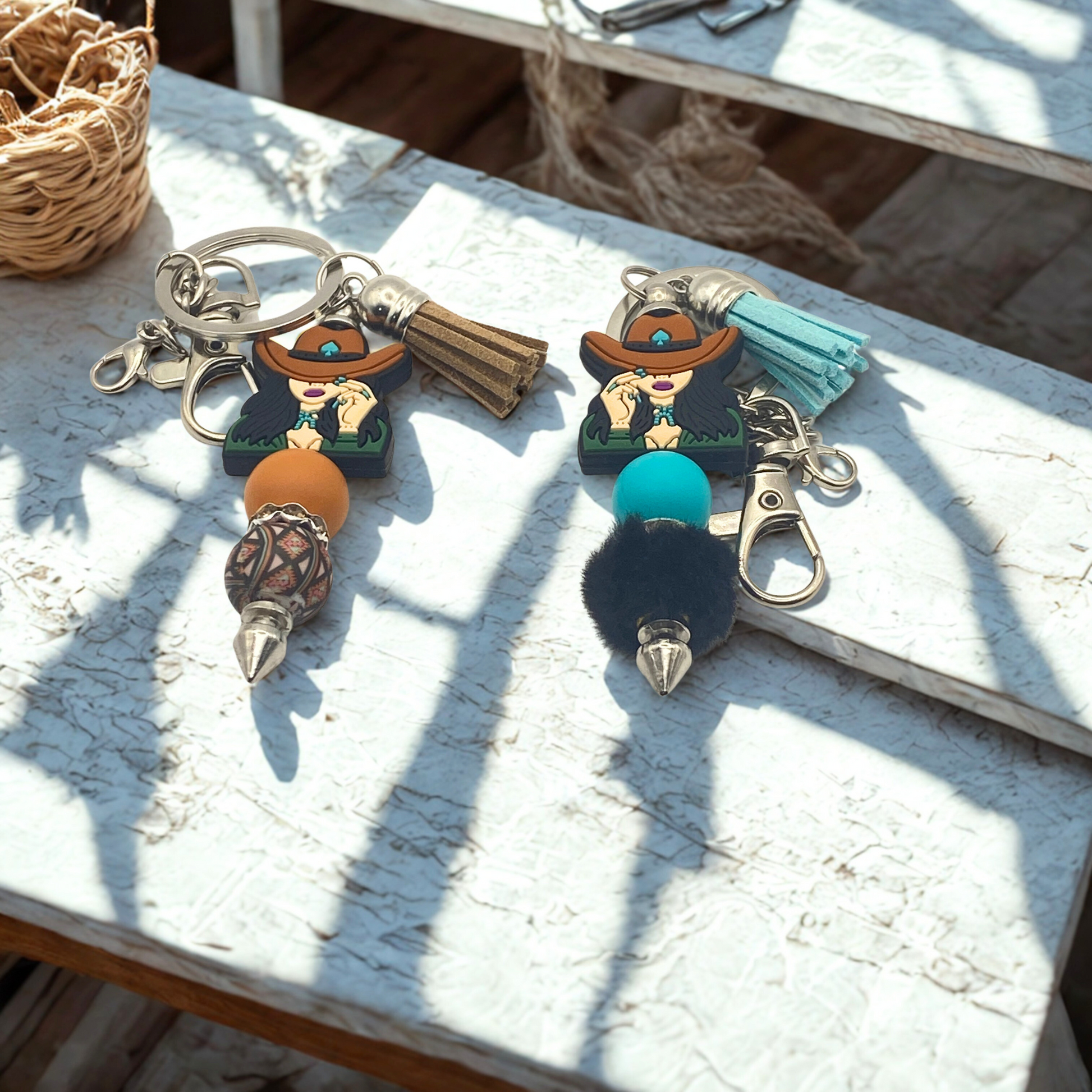 Two decorative keychains with characters and colorful poms on a wooden surface.