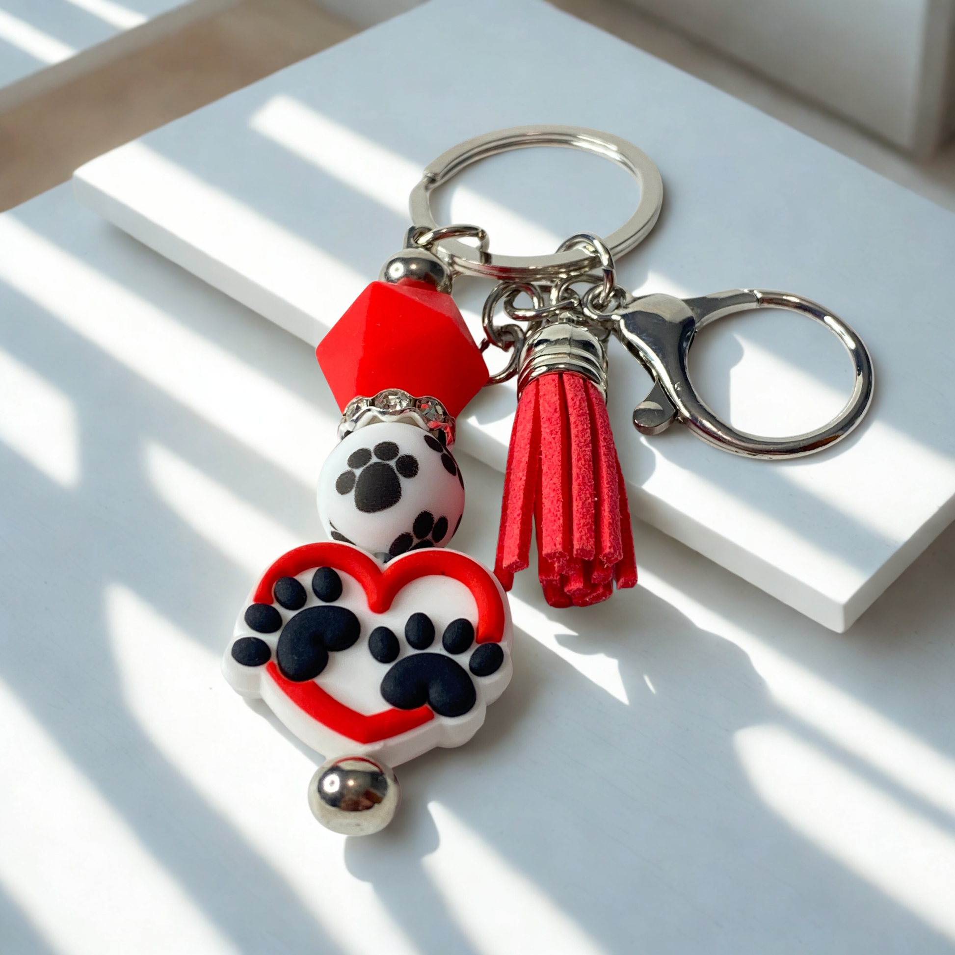 Keychain with paw prints and heart design on a white surface