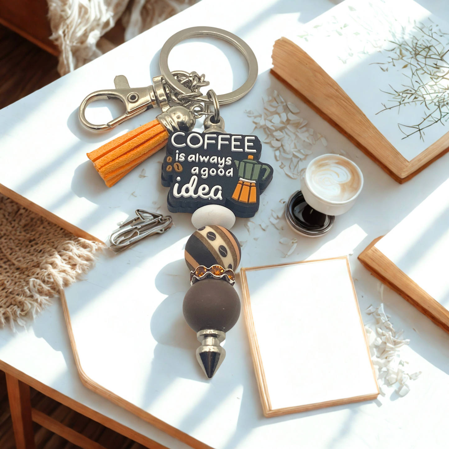 Keychain with 'Coffee is always a good idea' text on a table with decor items.