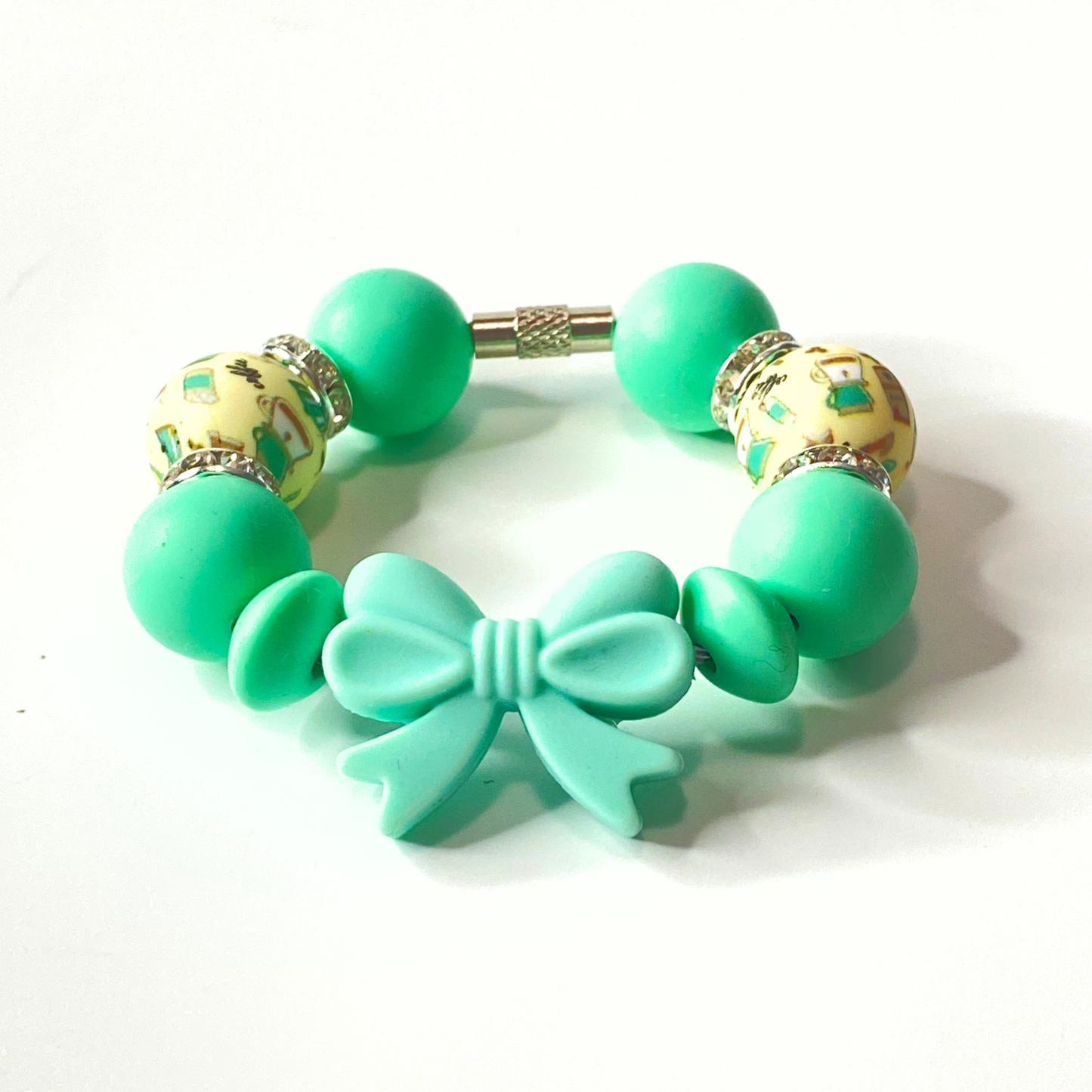 Green bracelet with bow charm on a white background