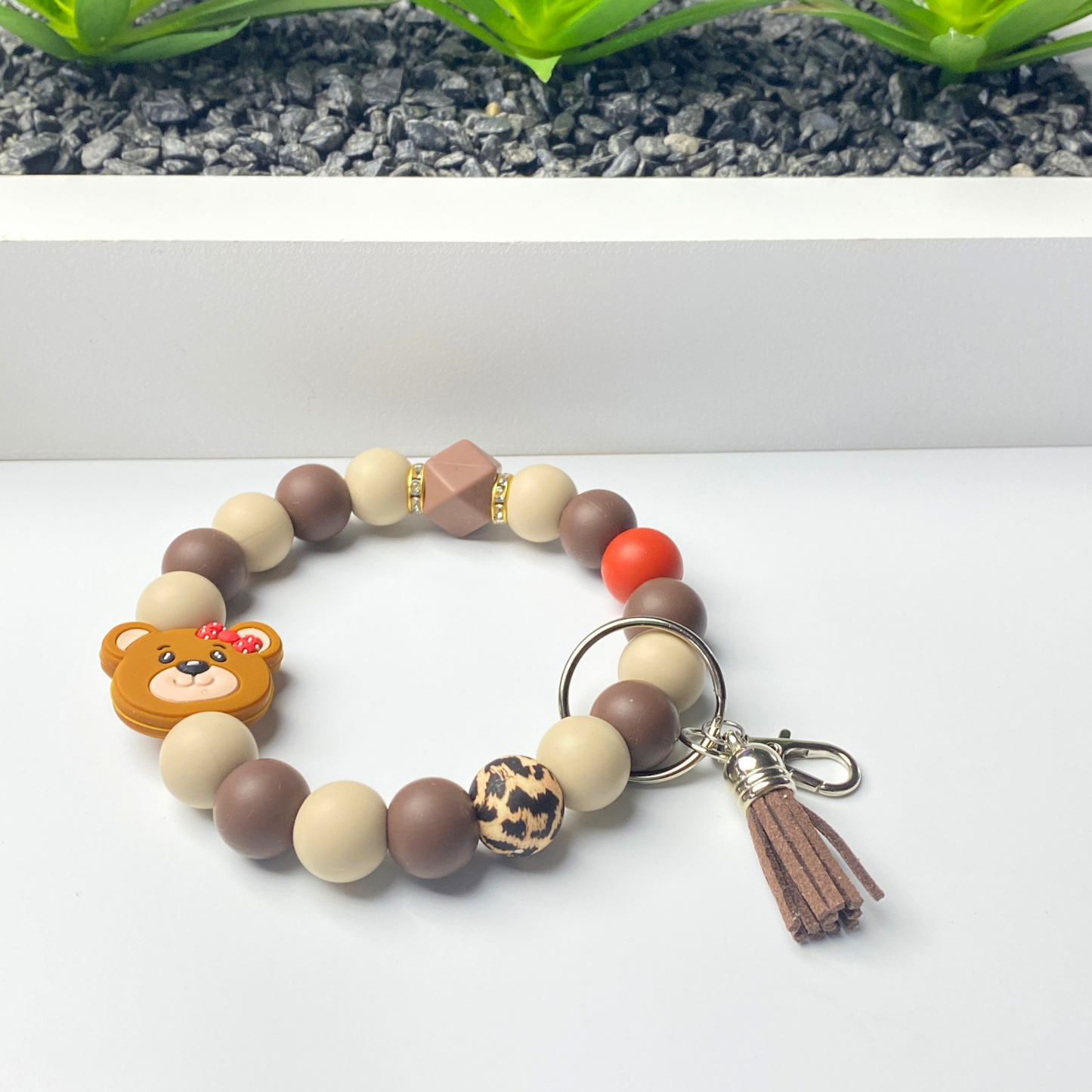 Bracelet with teddy bear charm and keychain on a white surface