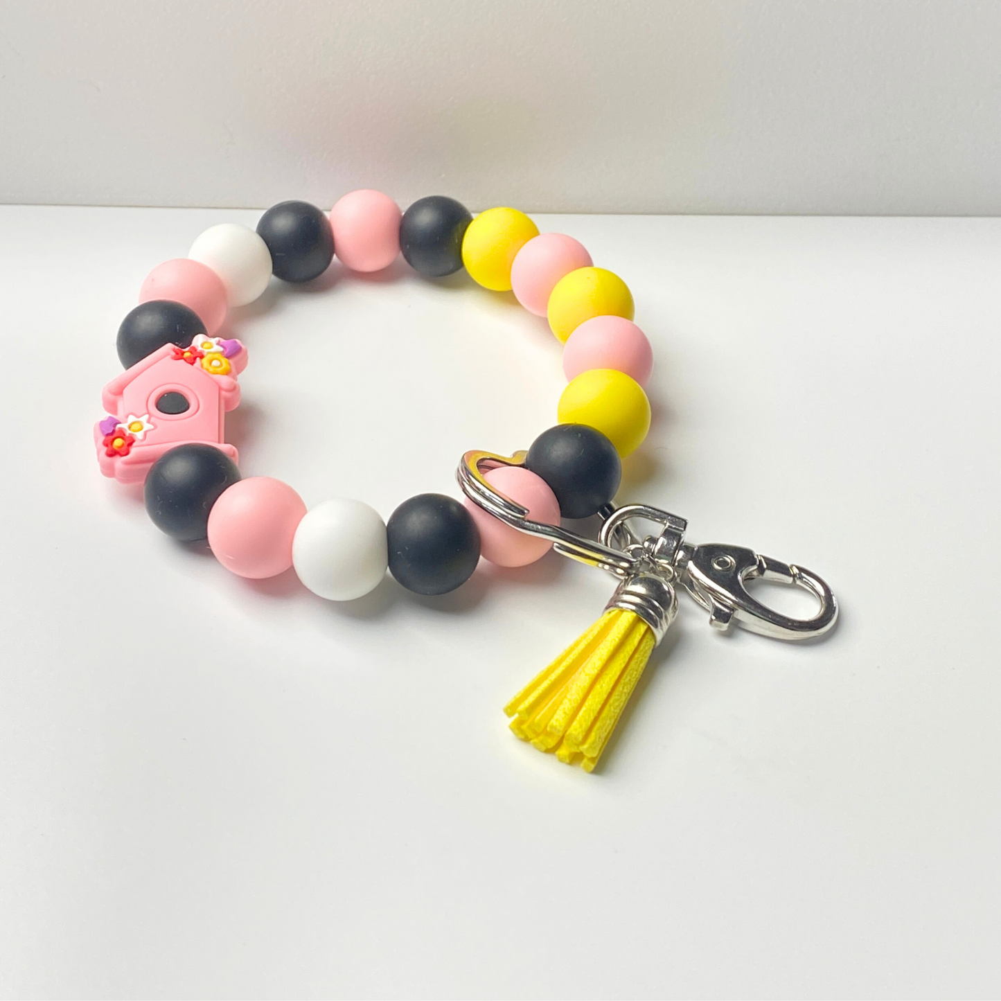 Colorful beaded keychain with a yellow tassel on a white background