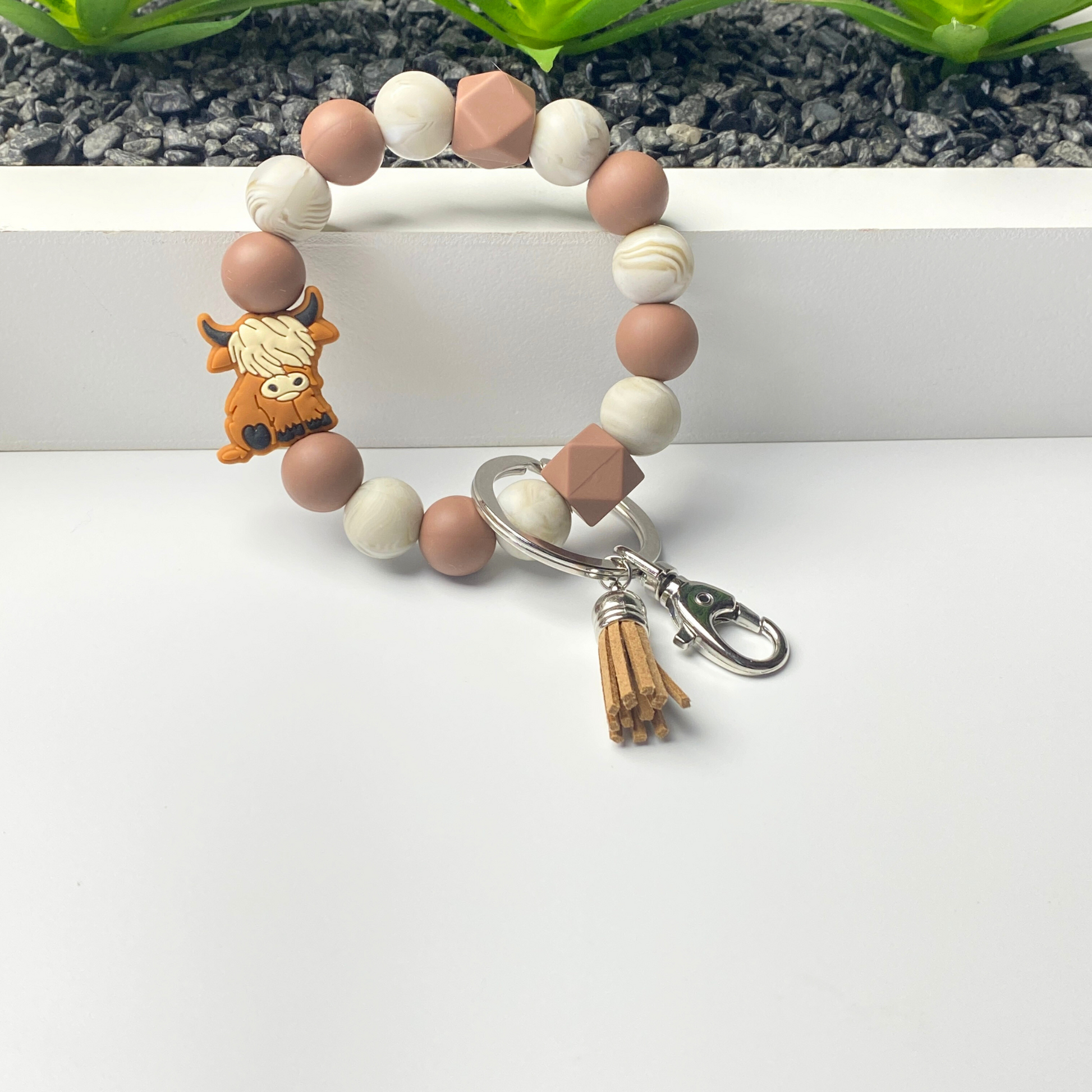 Beaded bracelet with a keychain charm on a white surface