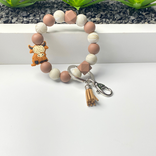Beaded bracelet with a keychain charm on a white surface