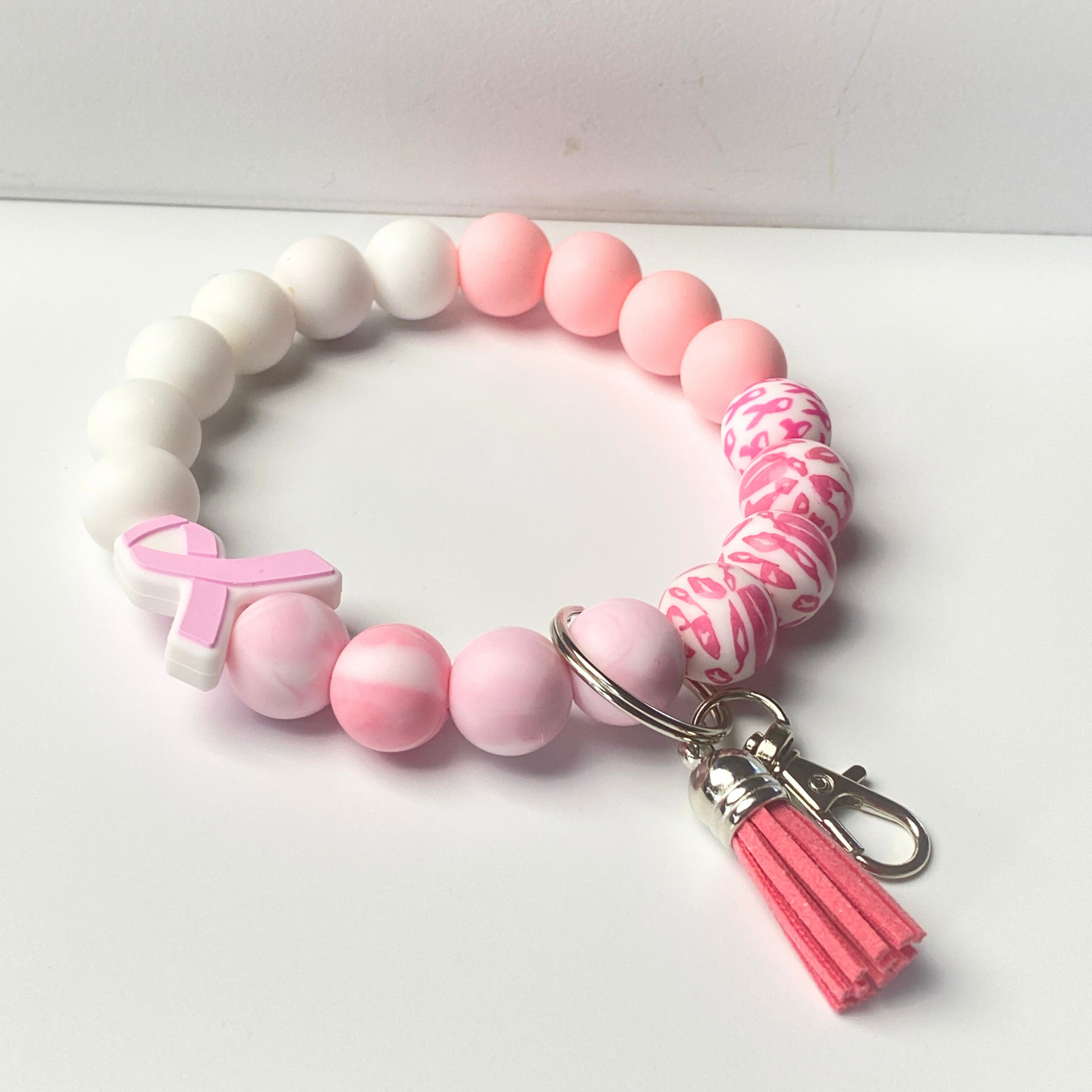 Pink and white beaded keychain with a breast cancer awareness ribbon on a white background