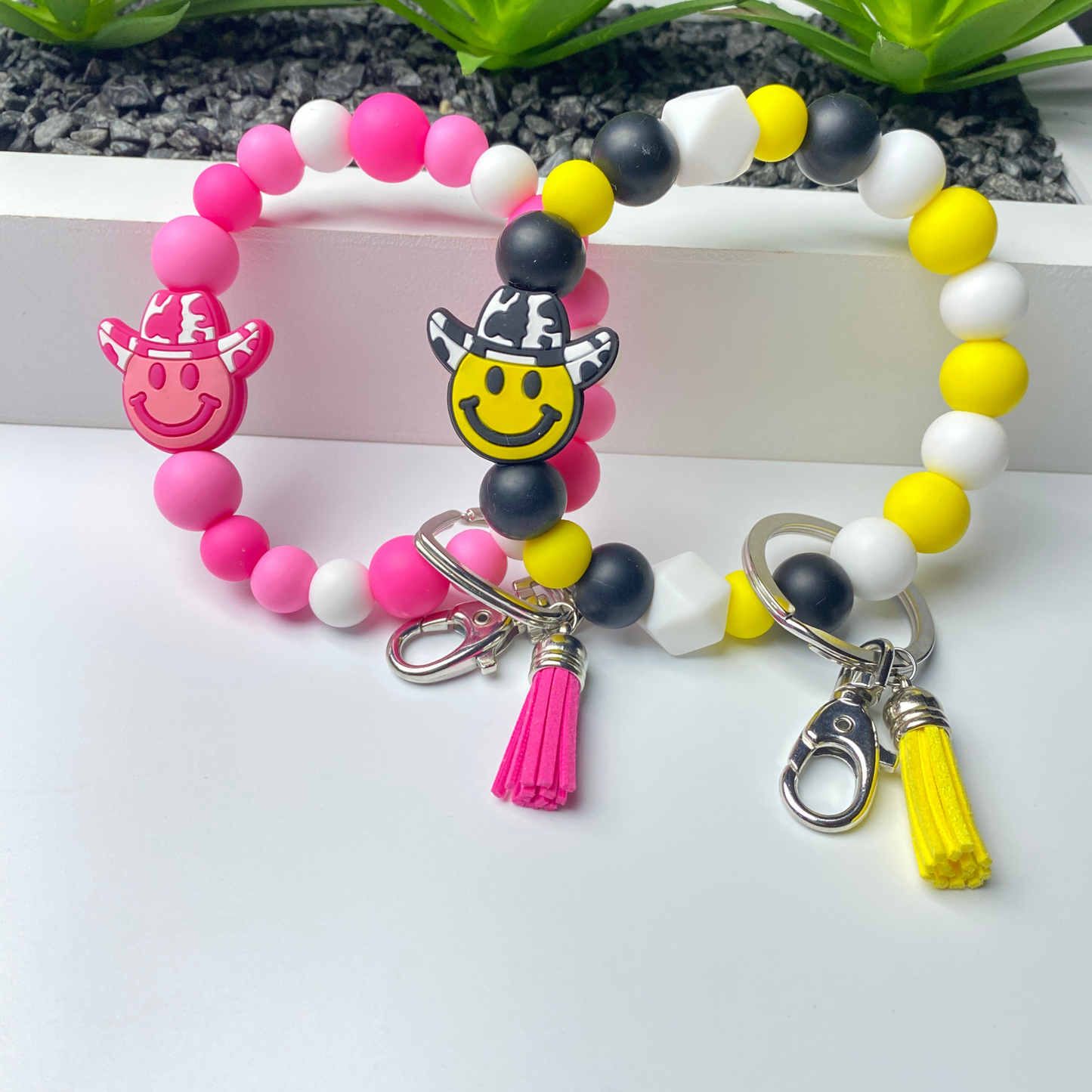Colorful beaded bracelet with smiley face charms and tassel on a white background
