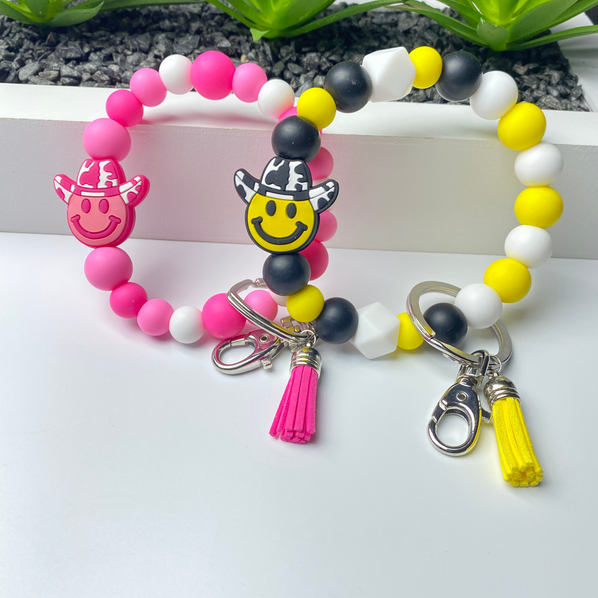 Colorful beaded bracelet with smiley face charms and tassel on a white background