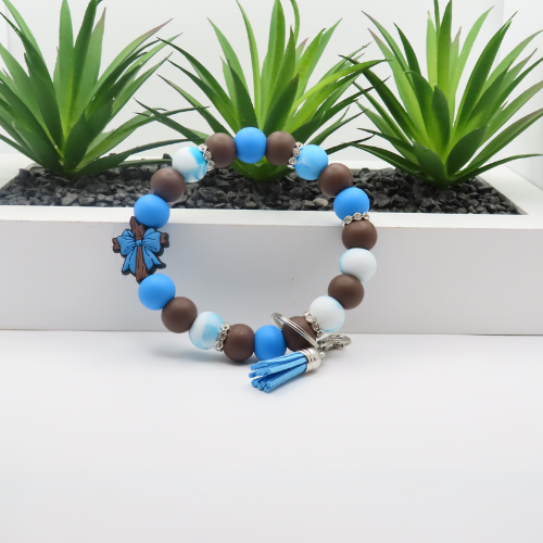 Bracelet with blue, brown, and white beads on a white surface with plants in the background