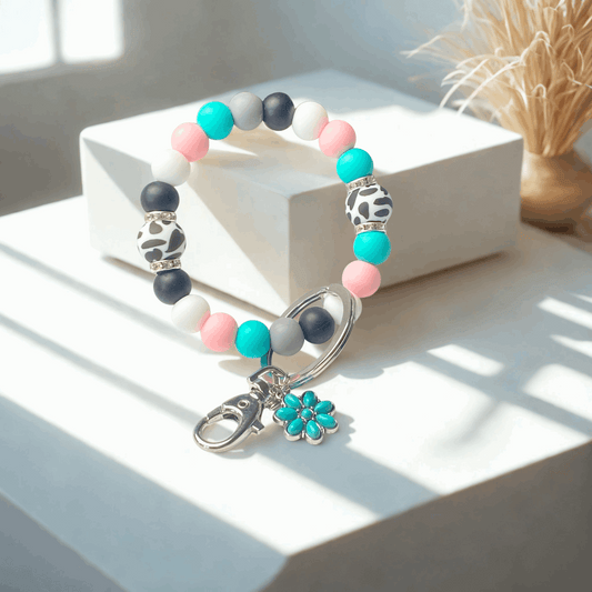 Beaded keychain with colorful beads and a flower charm on a white surface.