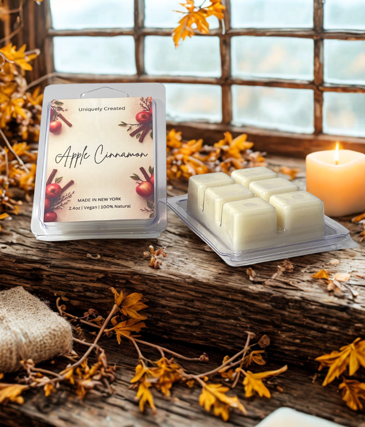 Apple Cinnamon wax melts packaging on a wooden surface with a candle and autumn leaves.