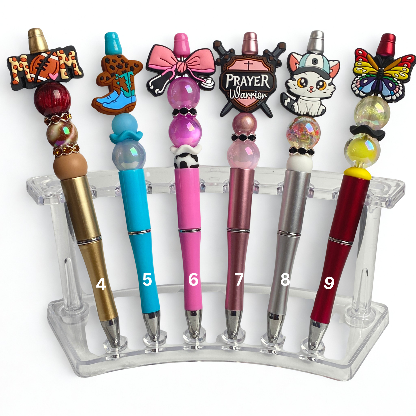 Set of decorative pens with unique designs on a clear stand