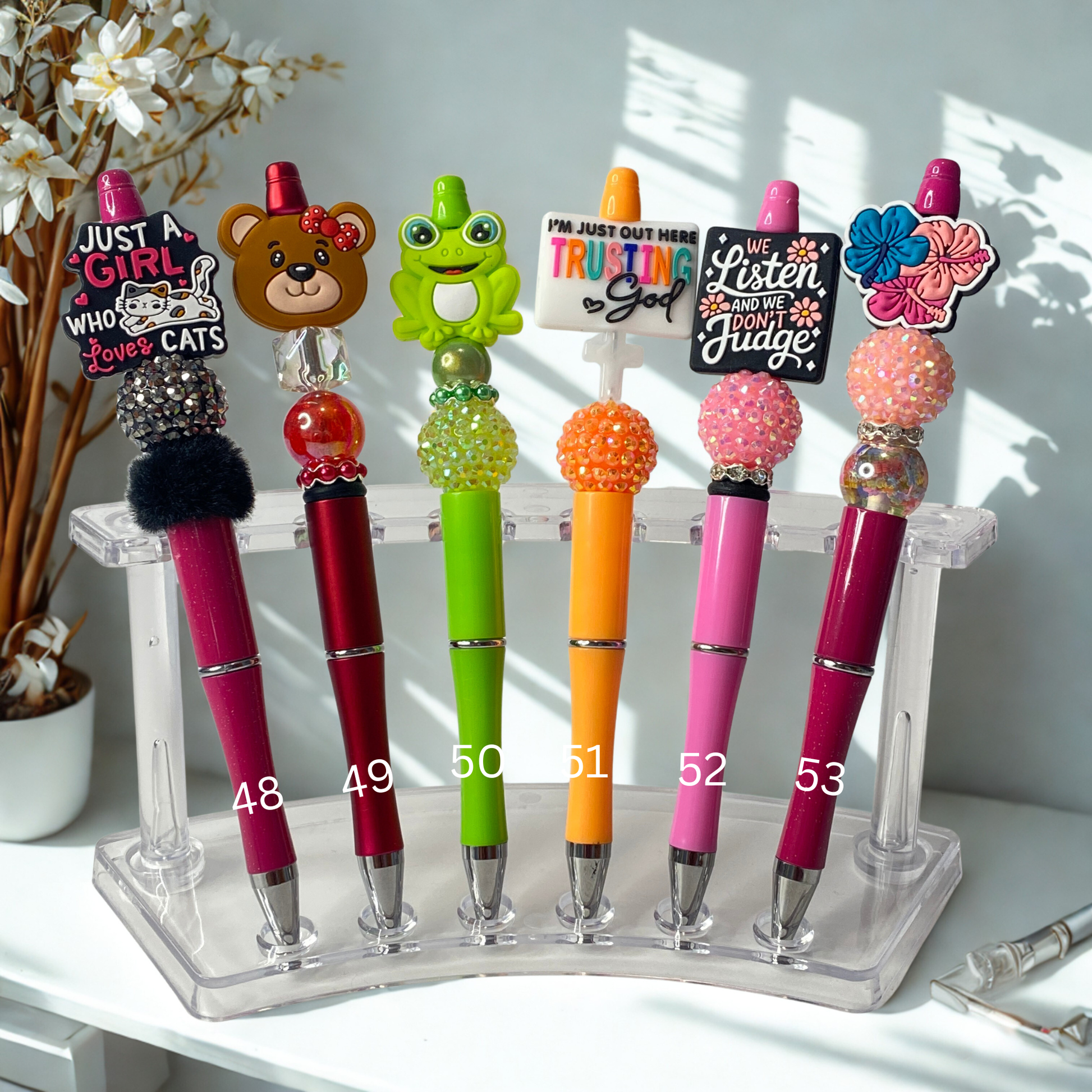 Colorful pens with various designs on a stand against a light background