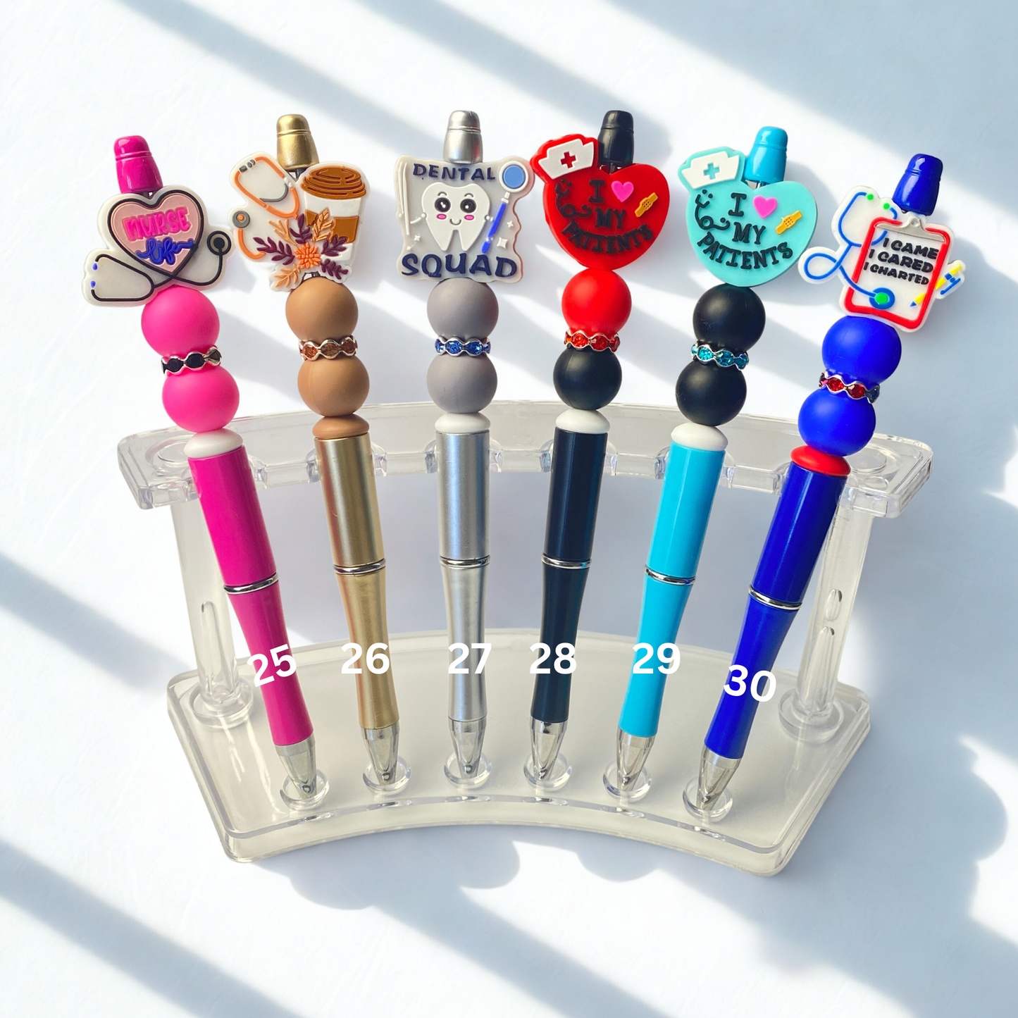 Set of colorful pens with decorative tops on a clear stand