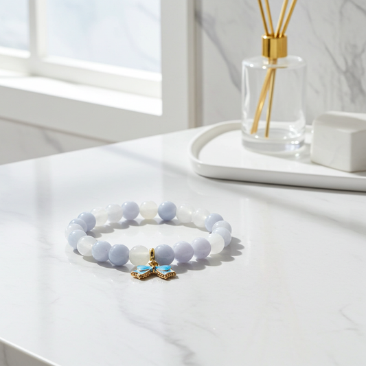 White beaded bracelet with a gold and blue charm on a white surface.