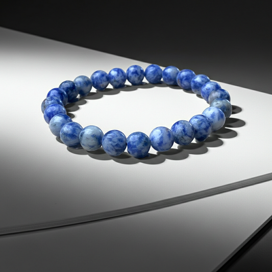 Blue beaded bracelet on a reflective surface with a dark background
