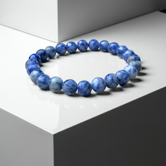 Blue beaded bracelet on a white surface with a gray geometric background