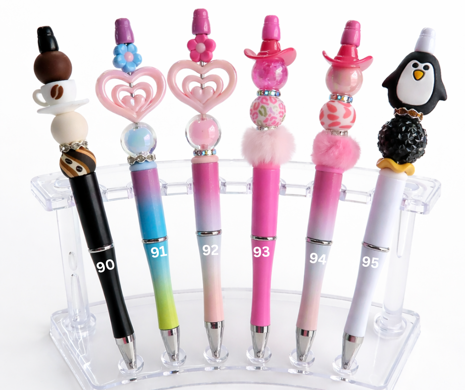 Set of decorative pens with unique designs on a clear stand