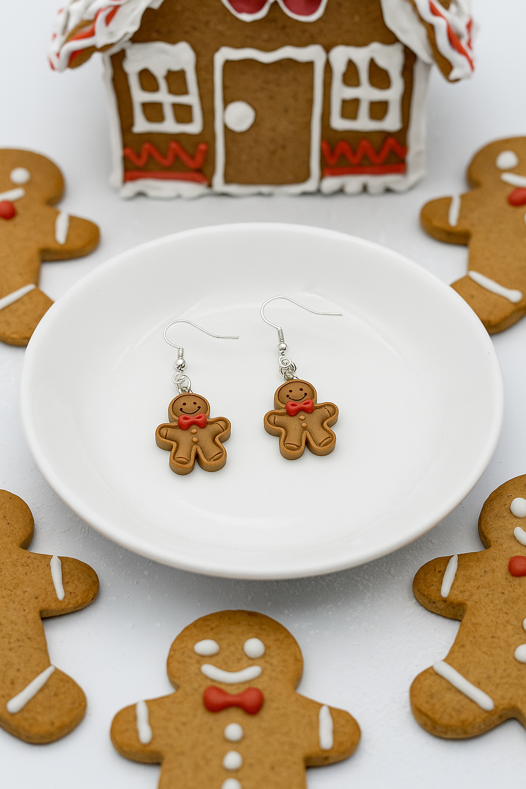 Gingerbread man earrings on a white dish with gingerbread cookies in the background