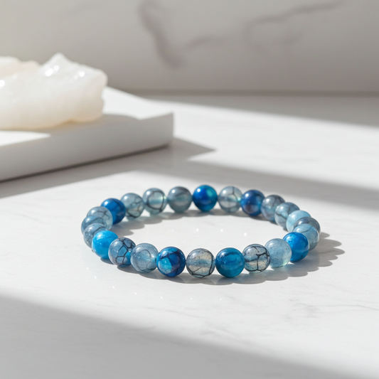 Blue beaded bracelet on a white surface with a soft background