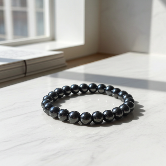 Black beaded bracelet on a light wooden surface with a window in the background