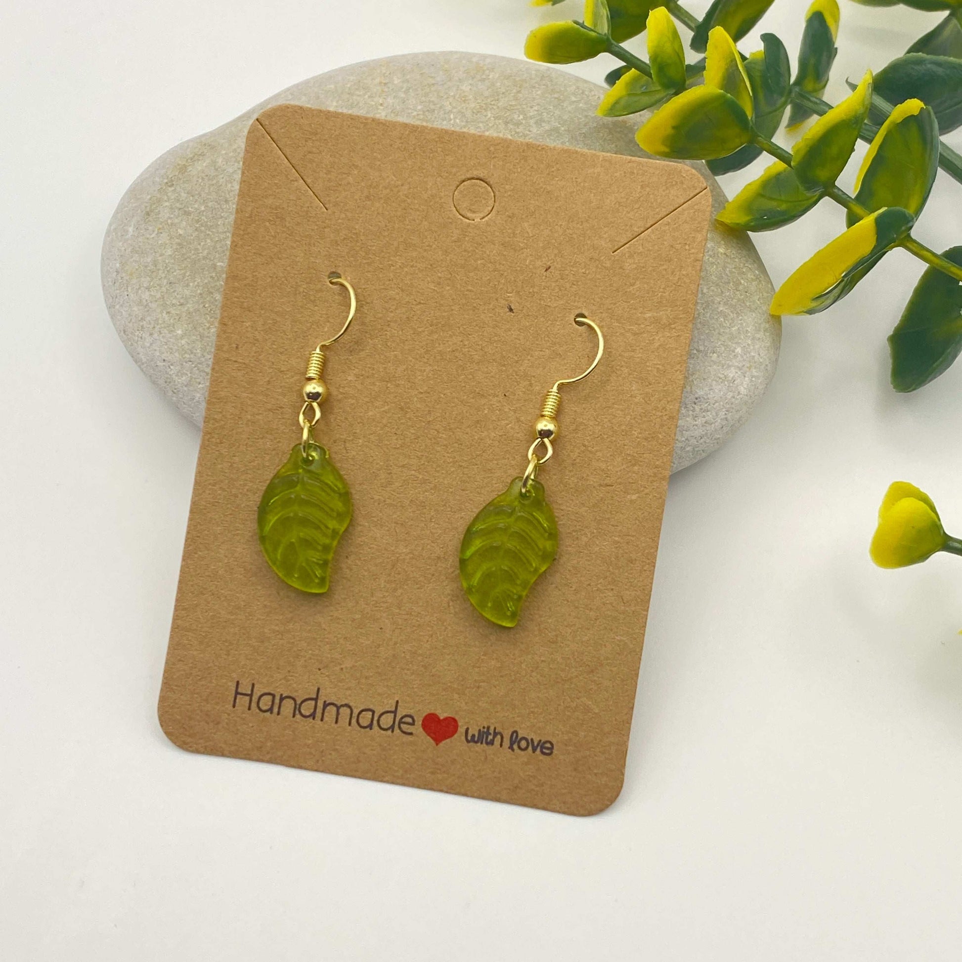 Green leaf-shaped earrings on a 'Handmade with Love' card with a natural background.