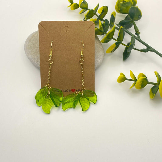 Green leaf-shaped earrings on a brown card with a natural background