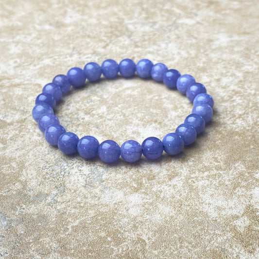 Purple beaded bracelet on a textured beige surface