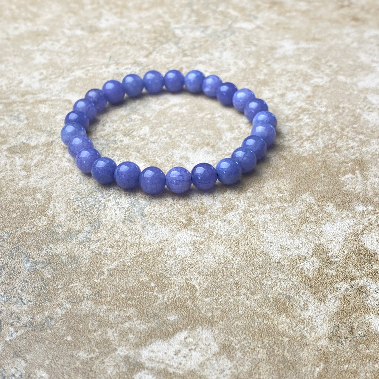 Purple beaded bracelet on a textured beige surface