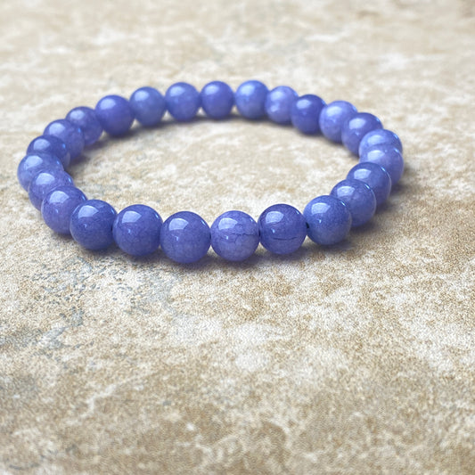 Purple beaded bracelet on a textured beige surface