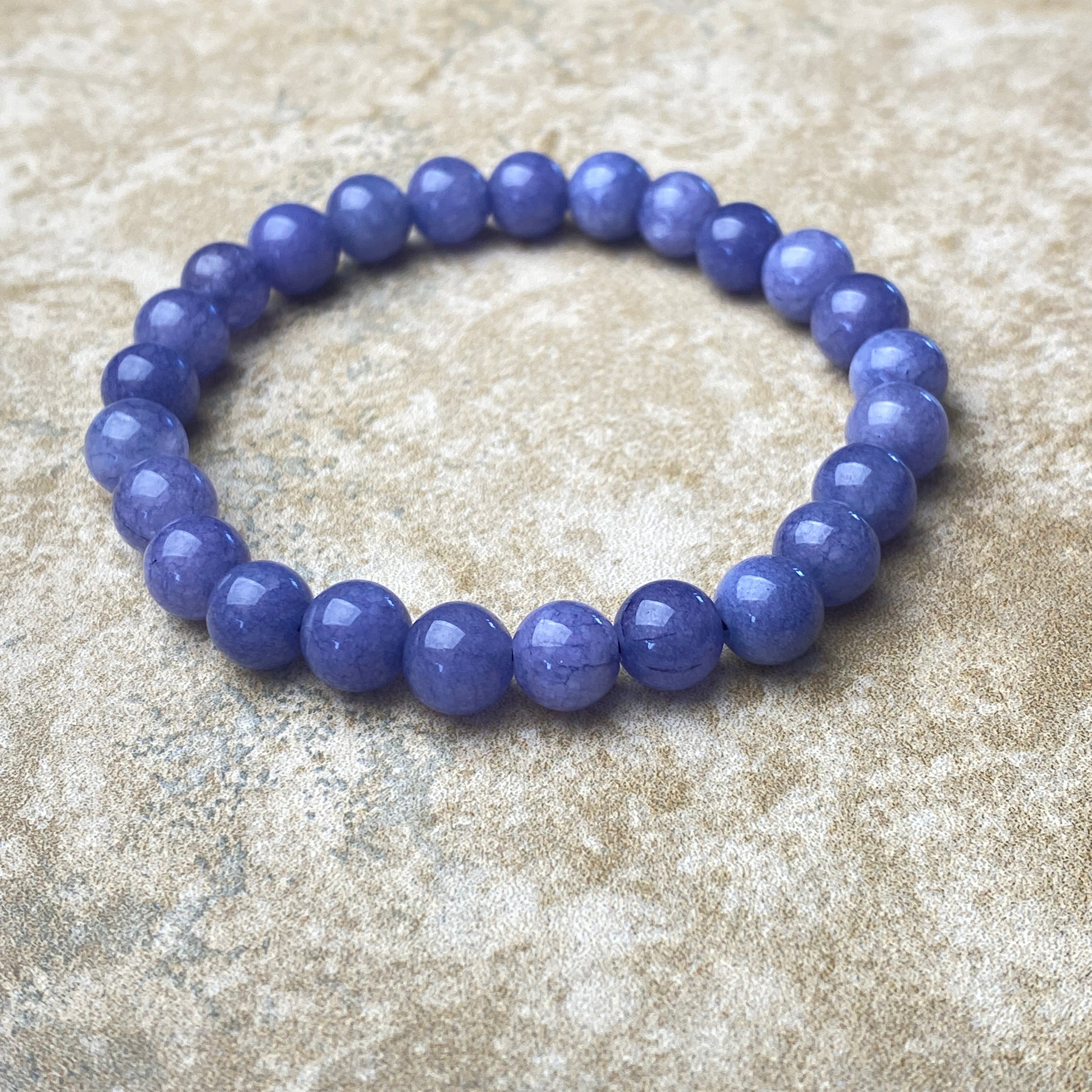 Purple beaded bracelet on a textured beige surface