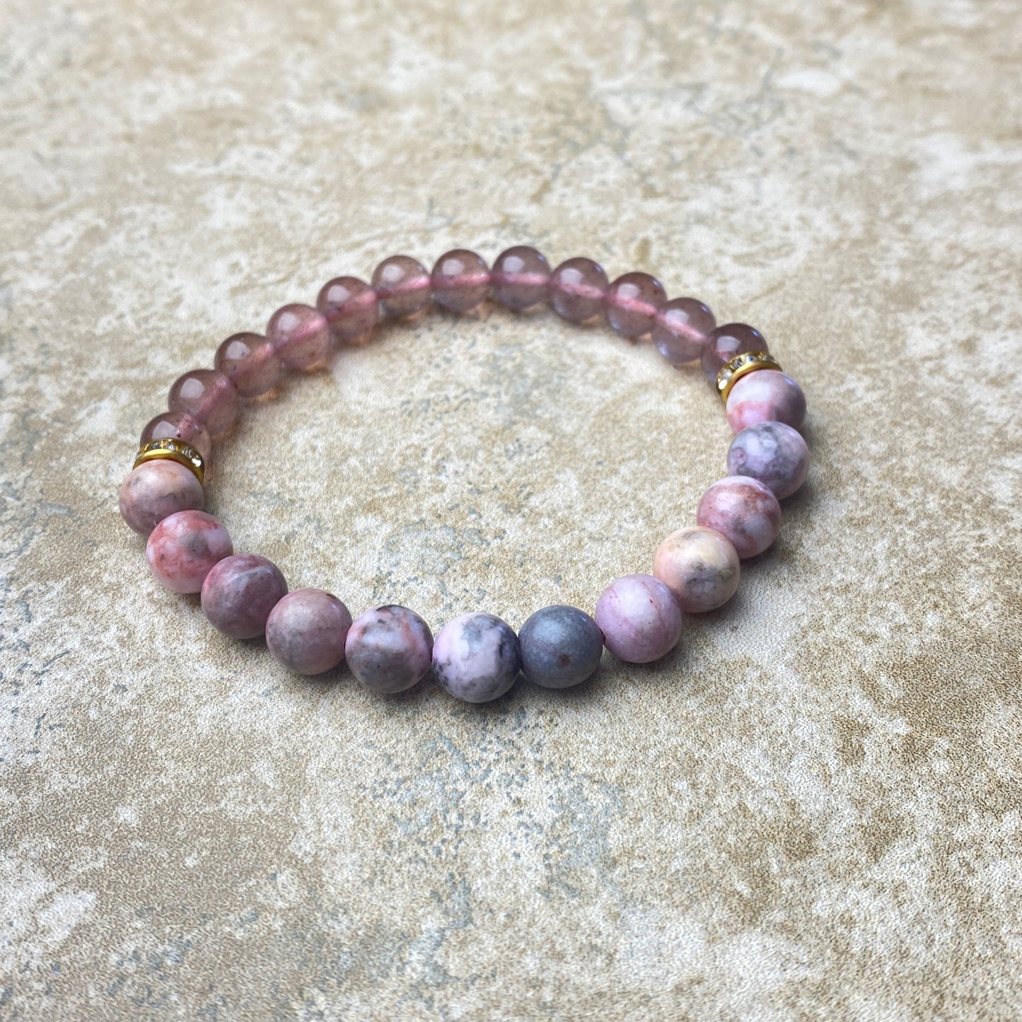 Beaded bracelet with purple and pink stones on a textured surface