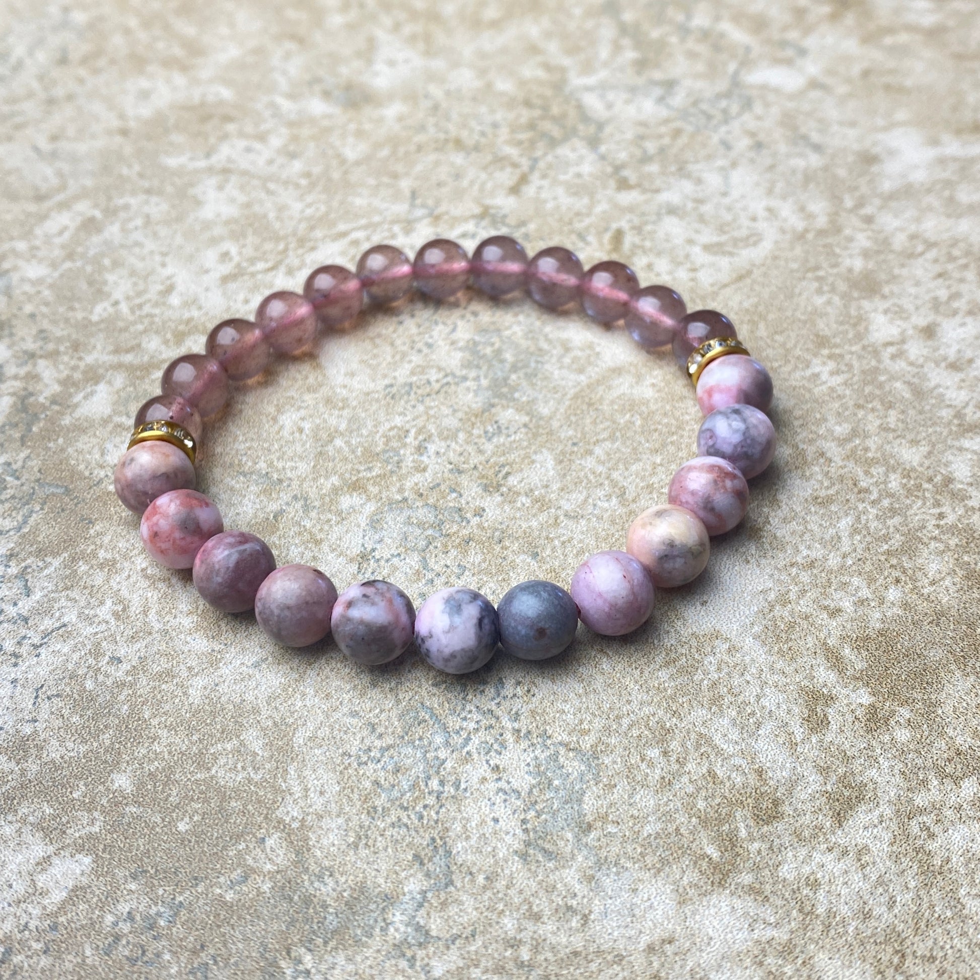 Beaded bracelet with purple and pink stones on a textured surface