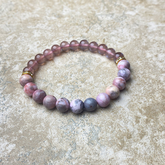 Beaded bracelet with purple and pink stones on a textured surface
