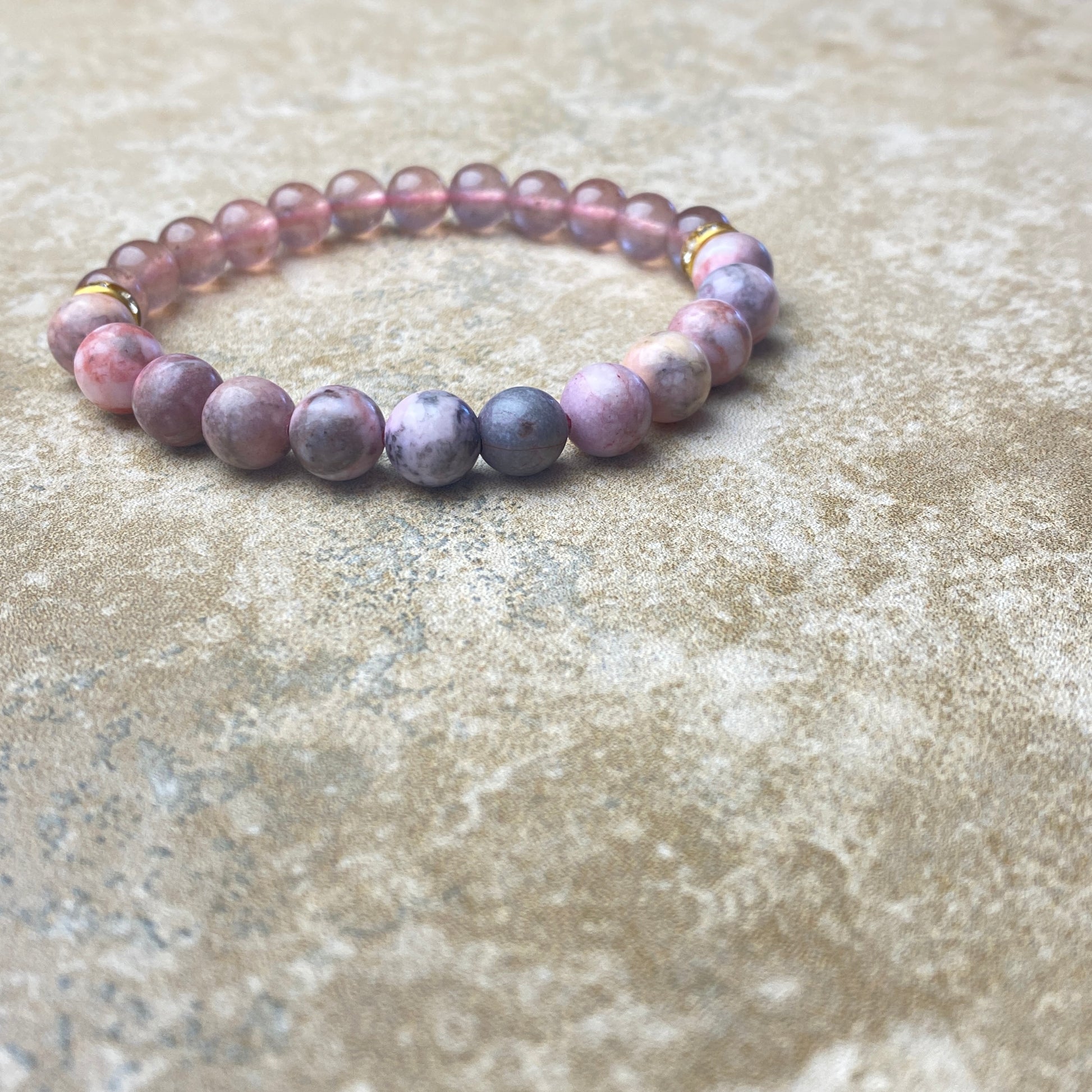 Beaded bracelet with purple and gray stones on a textured surface