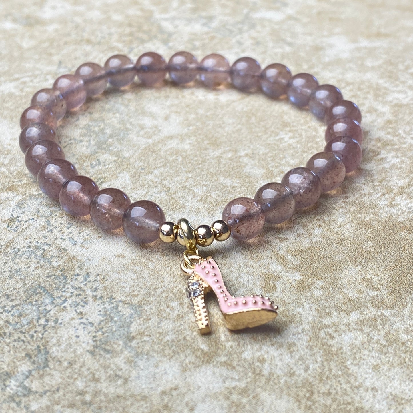 Beaded bracelet with a high heel charm on a textured surface