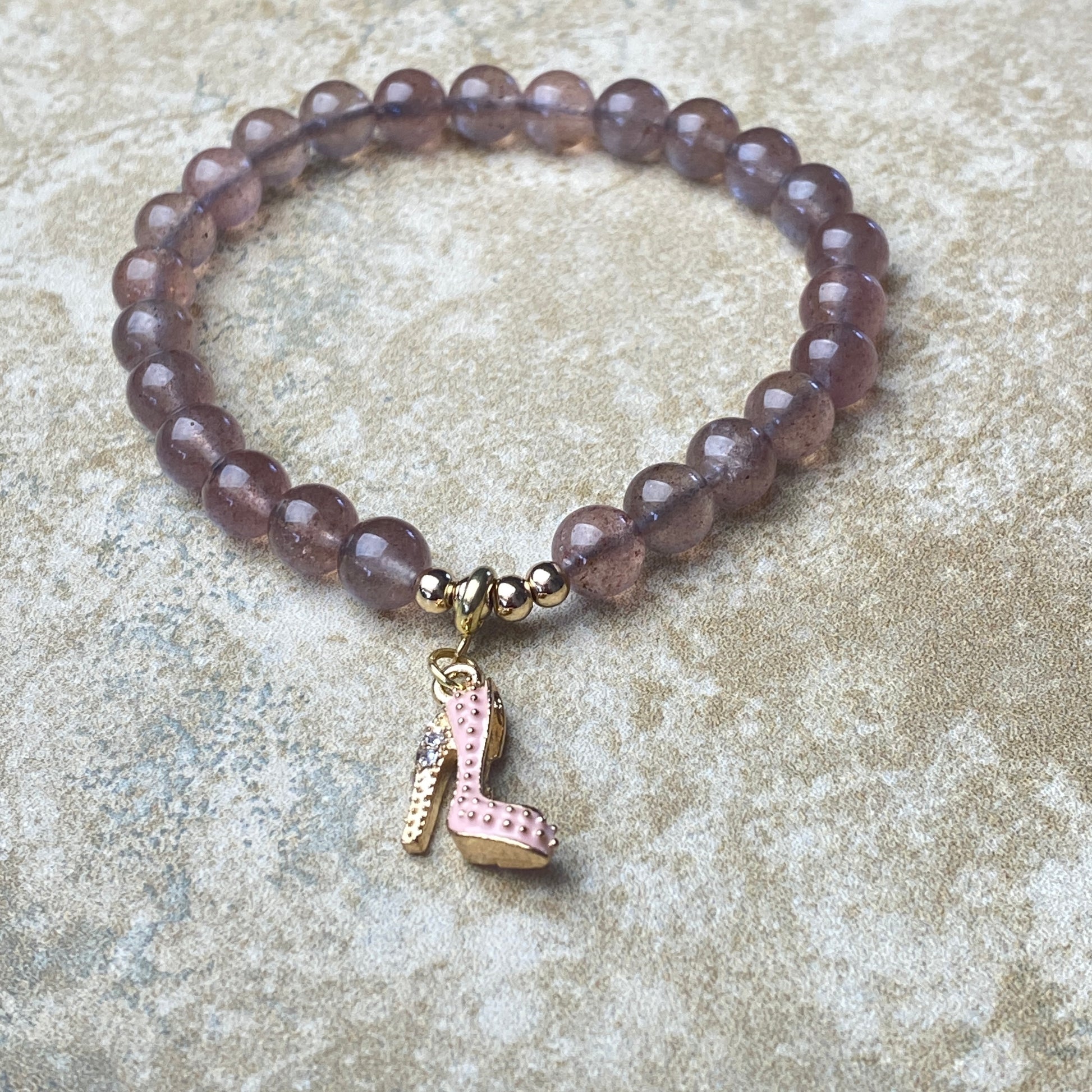 Bracelet with purple beads and a charm on a textured surface