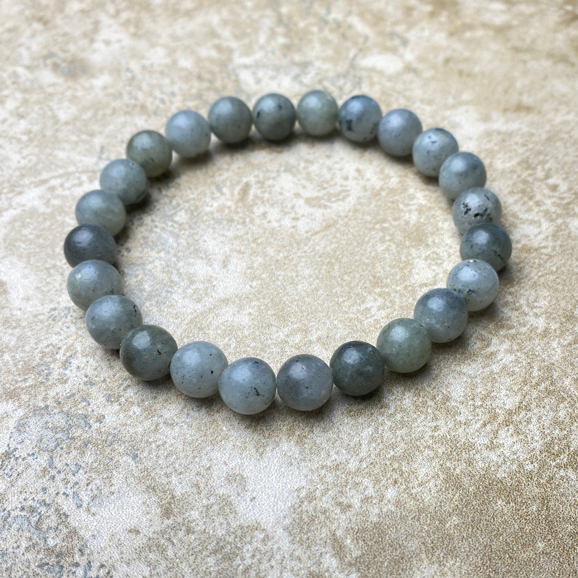Gray beaded bracelet on a textured beige surface