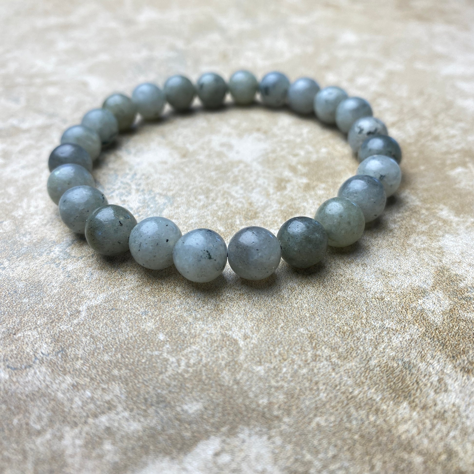 Gray beaded bracelet on a textured beige surface